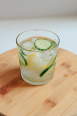 glass of water with cucumber on wooden background
