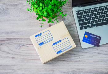 Top view with copy space, on the desk table. Credit card is placed at laptop and Shipping box. Online shopping concept.