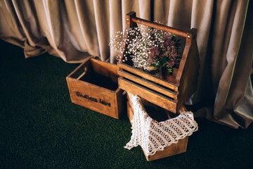 Decorations of wood and wild flowers are served on a festive table in a rustic style for a wedding ceremony. Wooden interior of a restaurant for a party. Lace in the design of the wedding.