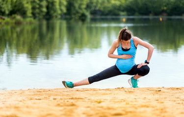 Pregnant woman doing fitness exercises at lakeside, sport during pregnancy