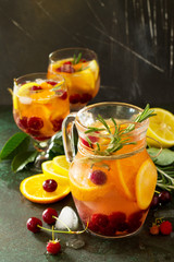Homemade refreshing wine sangria or punch with fruits. Sangria cocktails with fresh fruits, berries and rosemary on dark a stone or slate background. Copy space.