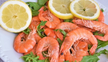 large red shrimps, arugula leaves and lemon wedges