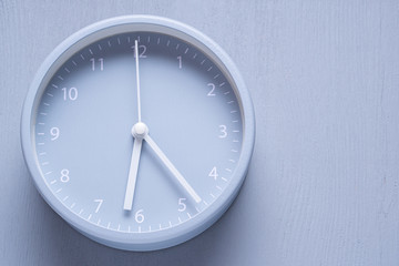 Gray alarm clock on gray wooden background.