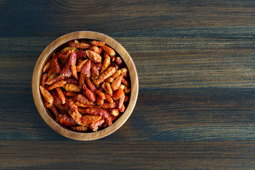 Fototapeta na wymiar Dried bird's eye chili peppers in a wooden bowl. Dark wooden table, high resolution, negative space