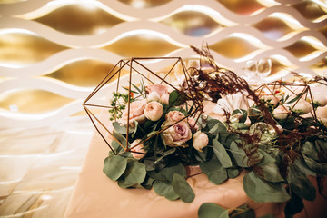 Wedding. Banquet. Beautiful and creative composition of a variety of pale pink flowers and candles that decorated the table for the newlyweds. Modern wedding decoration with geometric elements.
