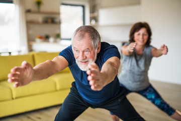 Fototapeta na wymiar A senior couple indoors at home, doing exercise indoors.