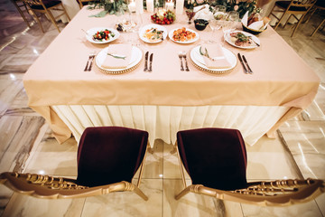 Wedding. Banquet. Beautiful and creative composition of a variety of pale pink flowers and candles that decorated the table for the newlyweds. Modern wedding decoration with geometric elements.