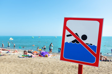 A sign on the beach is not allowed to swim! People bathe and rest on the sea in spite of the sign and ban.