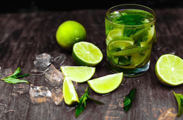 Cocktail mojito with mint, cold drink or beverage with ice and water drops on black background. Selective focus