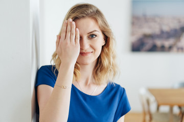 lächelnde frau hält eine hand vor ihr auge