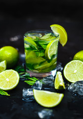 Cocktail mojito with mint, cold drink or beverage with ice and water drops on black background. Selective focus