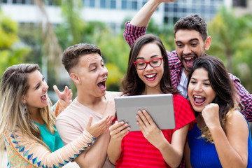Erfolgreiche junge Studentin mit Tablet und Freunden
