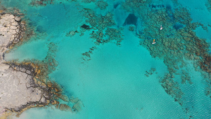 Fototapeta na wymiar Aerial top view photo of men practising wind surfing in exotic paradise open ocean bay with crystal clear turquoise sea