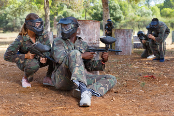 Two opposing teams shooting on paintball playing field outdoors