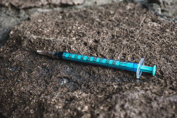 used syringe on concrete, drug addiction