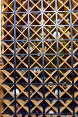 Wine bottles behind a metal security screen in the wine cellar of a house.