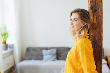 attraktive frau steht in ihrem wohnzimmer und schaut lächelnd zur seite