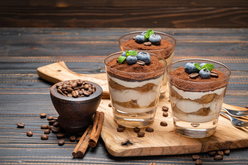 Classic tiramisu dessert in a glass with blueberries on wooden background