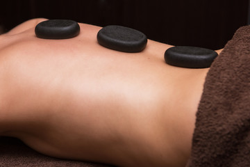Woman receiving a therapy with hot stones in spa center, closeup photo