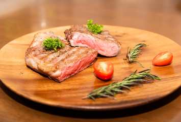 Fresh cooked half cut beef sirloin with cherry tomato and rosemary on top with parsley, Wood background