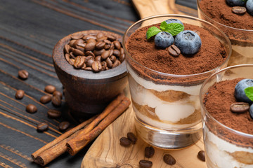 Classic tiramisu dessert in a glass with blueberries on wooden background