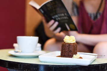 cake with a cup of coffee and someone reading a book