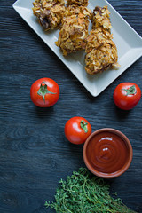 Roasted chicken drumsticks on a plate. Breaded chicken drumsticks, fried chicken. Dark wooden background.