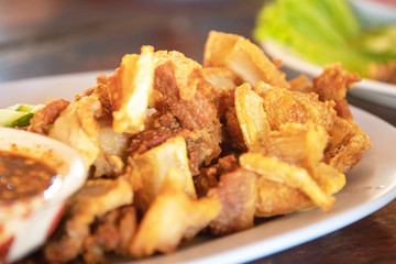 Deep fried crispy pork belly sliced cooked with salt and Thai spicy dipping sauce (Jaew sauce).