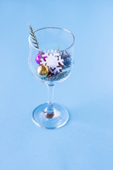 Christmas tree toys lie in a glass on a blue background, minimalism