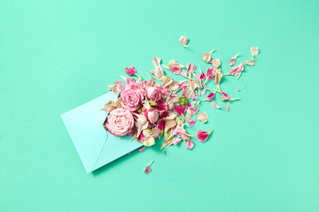 Fresh pink roses in handmade envelope on a turquoise background.