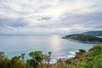 Beautiful landscape with ocean shore, green hill, cloudy sky. Phuket, Thailand.