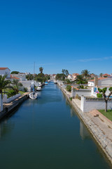 Fototapeta na wymiar Amazing view on marine canal with boats and white houses. Resort town landscape with palm trees, little Spanish Venice, Empuriabrava. Rich lifestyle, Summertime, calm scene. Perfect vacations.