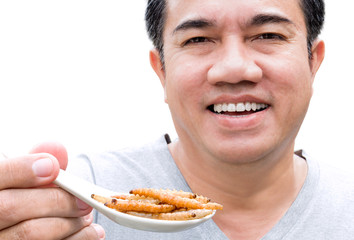 Food Insect: Man hand holding spoon eating Bamboo Worm insect or Bamboo Caterpillar deep-fried as food on white background, is good source of meal high protein edible for future. Entomophagy concept.