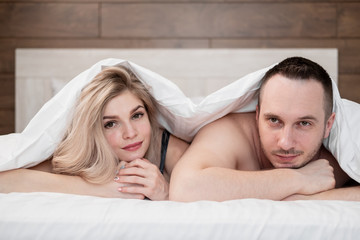 A married couple, a man and a woman, are lying in bed, hugging and sleeping.