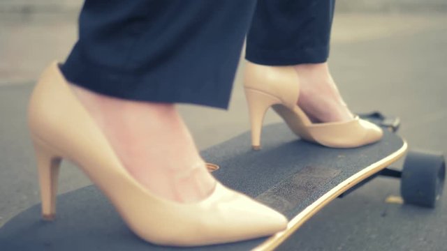close-up. women's beige shoe on a black skate board. Modern business woman in beige pumps shoes, rides on an electric board along a city street. The concept of achieving the goal and leadership