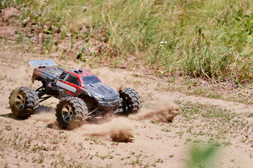 Radio controlled car model in race on the sandy road.