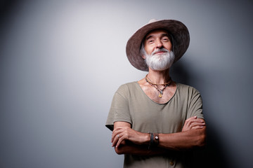 Middle aged traveler. Studio portrait of handsome senior man with gray beard and hat.