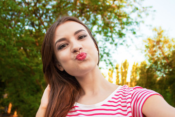 Pretty smiling girl making selfie, long-haired brunette in white clothes, closeup