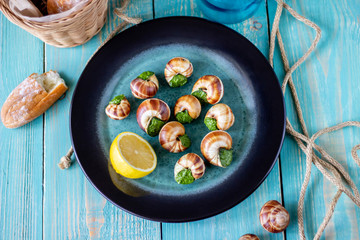 Bourguignonne snail with lemon. Blue wooden background.