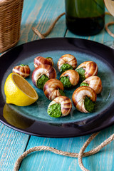 Bourguignonne snail with lemon. Blue wooden background.