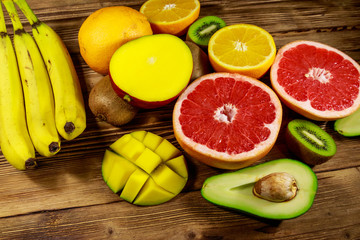Assortment of tropical fruits on wooden table. Still life with bananas, mango, oranges, avocado, grapefruit and kiwi fruits