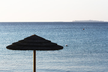 Straw umbrella against blue sea and sky