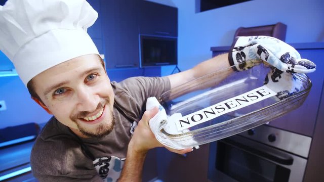 Professional cook making you some nonsense dish 4K. Wide view close-up on person face and dish in focus, smiling into the camera with kitchen in the background out of focus.