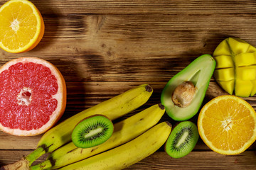 Assortment of tropical fruits on wooden table. Still life with bananas, mango, oranges, avocado, grapefruit and kiwi fruits