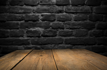 Old wood table with blurred concrete block wall in dark room background.