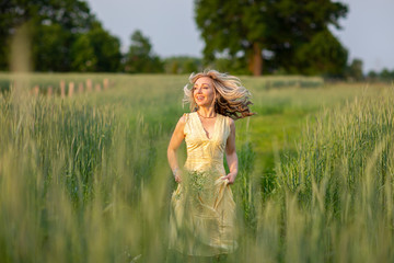 Fototapeta na wymiar Running blonde girl on the field. Life in the country.Summertime