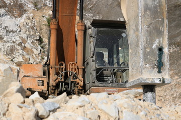 Fototapeta na wymiar Excavator with demolition hammer in a Carrara marble quarry. A l