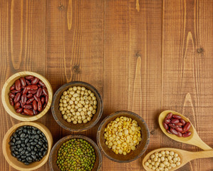 Flat lay,top view assorted beans including red bean,soybeans,black beans,mung beans on brown,beige wooden background with copy space 