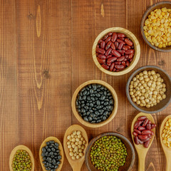 Flat lay,top view assorted beans including red bean,soybeans,black beans,mung beans on brown,beige wooden background with copy space 