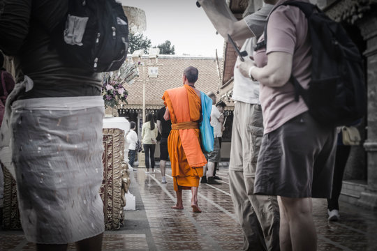 Selective Color image of barefoot Thai Monk walking among tourists in Doi Suthep.